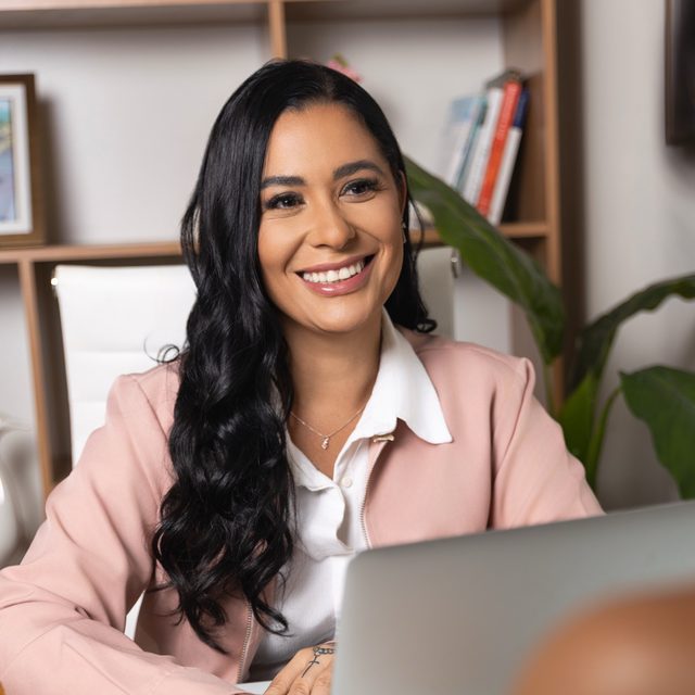 Monique Fahel sorrindo durante a consulta, com o notebook aberto